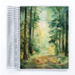 a spiral notebook with a painting of a forest scene