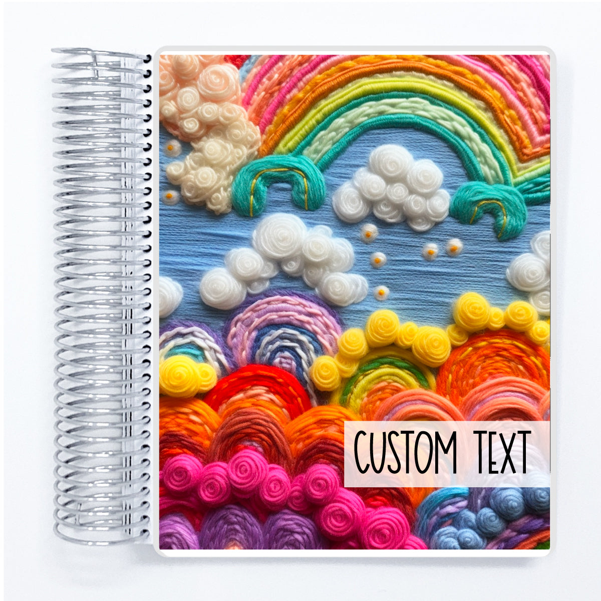 a spiral notebook with a picture of a rainbow and clouds