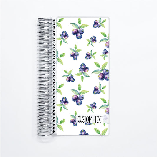a spiral notebook with a pattern of blueberries and leaves